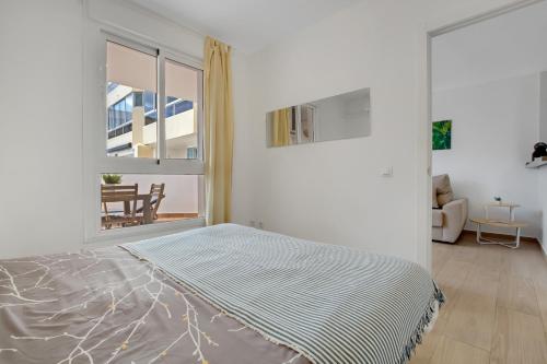 a white bedroom with a bed and a window at Vistamarina B105 by IVI Real Estate in Torremolinos