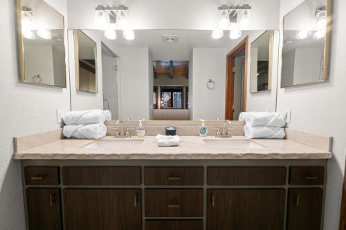 une salle de bain avec deux lavabos et un grand miroir dans l'établissement Evergreen -LUXURY CABIN WITH A HOT TUB, GAME ROOM & 3 EN-SUITE BEDROOMS!, à Big Bear Lake