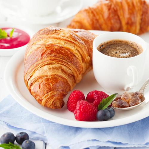 Um prato com um croissant, uma xícara de café e frutas vermelhas. em Mansarda romantica "Il nido delle rondini" em Conversano