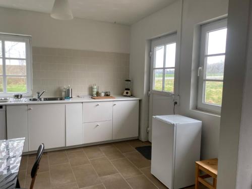 a kitchen with white cabinets and a sink and two windows at Countryside home 300m to the Fishing river Lille Ø in Langå