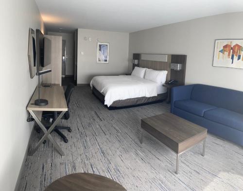 a hotel room with a bed and a blue couch at Holiday Inn Express & Suites Muskegon - Grand Haven by IHG in Muskegon