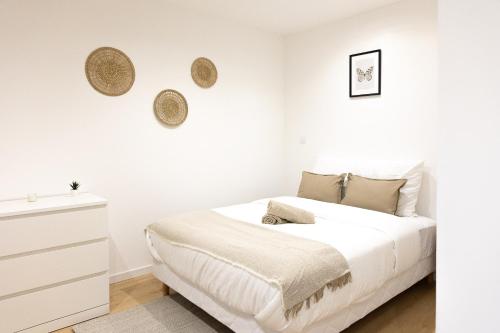 a white bedroom with a bed and a dresser at 1225Location in Cambrai