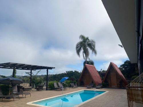 einen Swimmingpool mit Palmen und ein Haus in der Unterkunft Chácara Recanto das Aves in Pilar do Sul