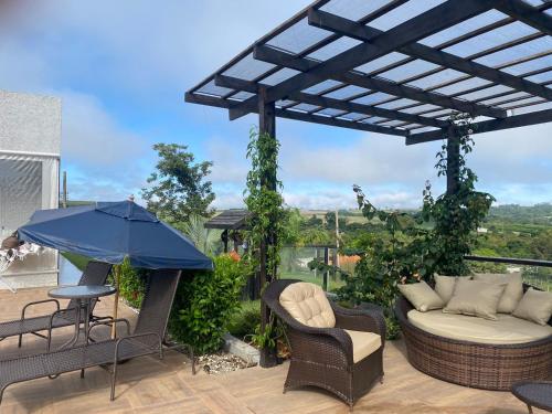 a patio with a blue umbrella and chairs and a table at Chácara Recanto das Aves in Pilar do Sul