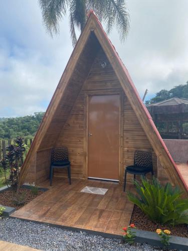 a triangular house with two chairs and a door at Chácara Recanto das Aves in Pilar do Sul
