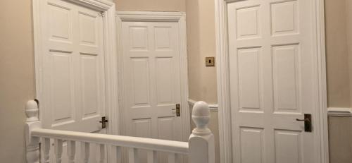 a hallway with two white doors and a staircase at Wood, Double Room in London in Great Warley Street