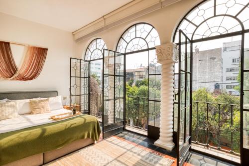 Un dormitorio con una cama y grandes ventanales. en Santa Casa by Tasman, en Ciudad de México