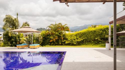 a swimming pool with two chairs and an umbrella at Malugo Campestre in Pereira