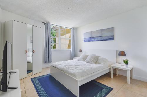 a white bedroom with a bed and a television at Lux Condo at Yacht Club 10 min from Beach in Miami