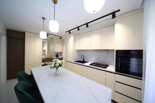 a kitchen with a white table with a vase of flowers at LUXURY EST ONE in Drobeta-Turnu Severin