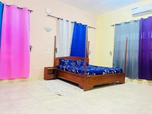 a bed in a room with purple and blue curtains at Timba-Day229 in Abomey-Calavi