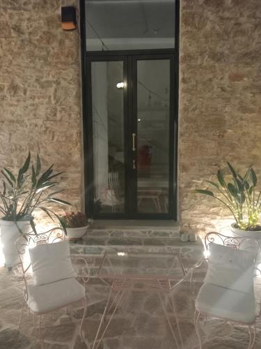 two white chairs sitting in front of a window at Stoa House Airport in Koropíon