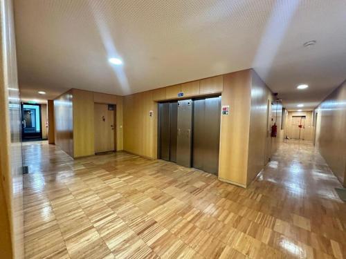 un pasillo vacío de un edificio de oficinas con puertas y suelo de madera en Premium Apartment at Quinta da Portela - Coimbra en Coímbra