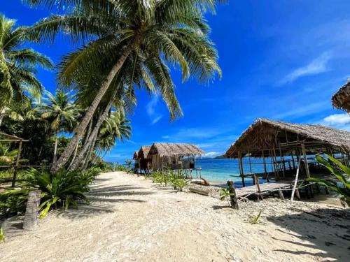 a beach with some straw huts and the ocean at Bonwau West Waigeo in Minyaifuin