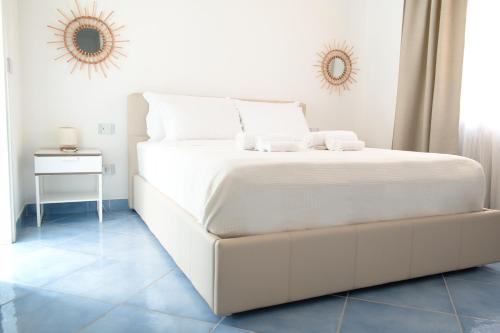 ein weißes Bett in einem weißen Schlafzimmer mit einem Spiegel in der Unterkunft Fountain House Sorrento in Sant'Agnello
