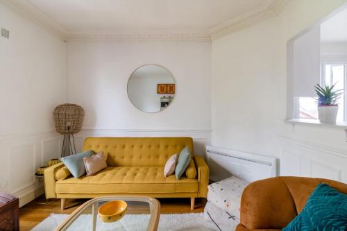 - un salon avec un canapé jaune et un miroir dans l'établissement Appartement Mosta - Welkeys, à Versailles