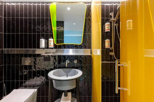 a bathroom with a sink and a mirror and a toilet at Adge Hotel and Residence - Adge King - Australia in Sydney