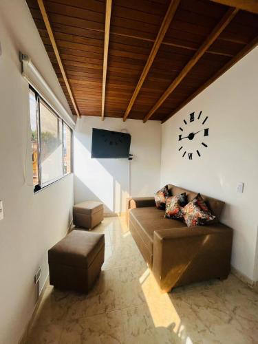 ein Wohnzimmer mit einem Sofa und einer Uhr an der Wand in der Unterkunft El Noral in Medellín