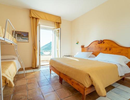 a bedroom with two beds and a large window at Hotel Belvedere in Sperlonga