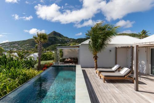a pool with chaise lounge chairs and a house at Le Sereno in Gustavia
