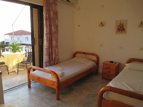 a bedroom with two beds and a balcony with a table at NICK STUDIOS previous NICK HOUSE in Plomarion