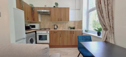 a kitchen with wooden cabinets and a table and a window at Botanic Residence in Liverpool