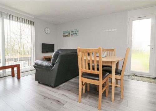 a living room with a table and a leather couch at Chalet at Penstowe Holiday Park Near Bude in Bude