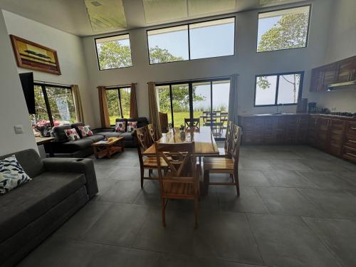 ein Wohnzimmer mit einem Tisch, Stühlen und Fenstern in der Unterkunft Canavida Villas & Resort in Uvita