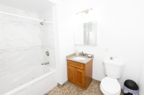 a bathroom with a toilet and a tub and a sink at Pristine 2-Bed Apt with Skyline Views - mins to NYC in Union City