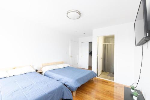 two beds in a room with white walls and wooden floors at Pristine 2-Bed Apt with Skyline Views - mins to NYC in Union City