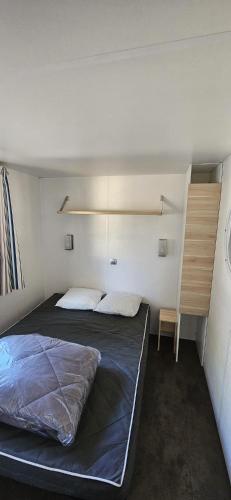 une petite chambre avec un lit et un bureau dans l'établissement Mobil home 4 pers ombragé climatisé camping Marvilla parc AGDE, à Agde