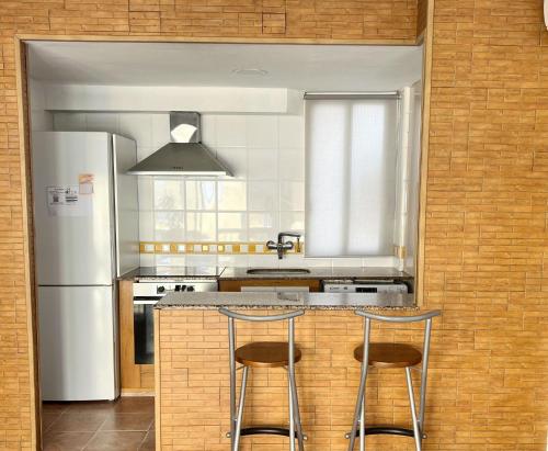 a kitchen with a white refrigerator and two bar stools at ACOGEDOR PISO EN CULLERA JUNTO AL MAR in Cullera