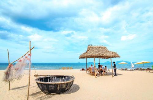 a wooden boat on a beach with a straw umbrella at Lama Beach Villa in An Bang