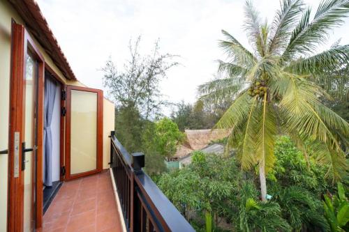 a balcony of a house with a palm tree at Lama Beach Villa in An Bang