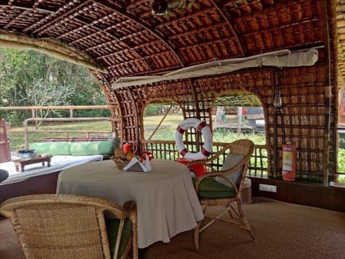 ein Zimmer mit einem Tisch und Stühlen in einer Hütte in der Unterkunft Spice Coast Cruises - Houseboat in Alappuzha