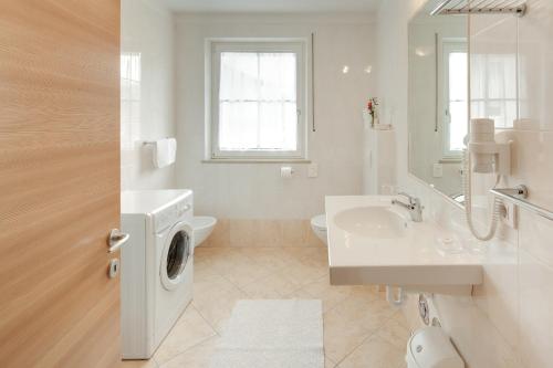 uma casa de banho branca com uma máquina de lavar roupa e um lavatório em Tirolerhof Pension em Naz-Sciaves