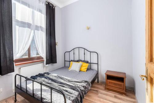ein Schlafzimmer mit einem Bett mit gelben Kissen und einem Fenster in der Unterkunft Charming central apartment in Krakau