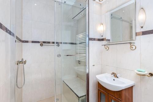 ein Bad mit einer Glasdusche und einem Waschbecken in der Unterkunft Charming central apartment in Krakau