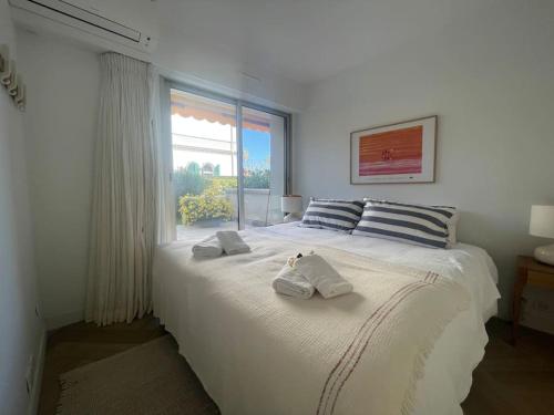 a white bedroom with a large bed with towels on it at Le Bluebay - Luxurious 2 bedrooms seaview swimming pool carpark in Cannes