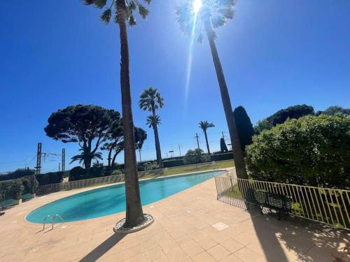 une piscine entourée de palmiers dans un parc dans l'établissement Le Bluebay - Luxurious 2 bedrooms seaview swimming pool carpark, à Cannes