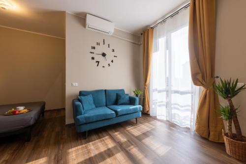 a living room with a blue couch and a clock on the wall at Comfort Home Rho Fiera in Rho