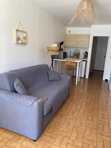 un salon avec un canapé bleu et une cuisine dans l'établissement studio cabine,4 personnes ,rénové,au calme,200 m de la plage,parking privé, à Sète