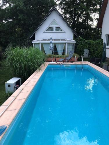 a large blue swimming pool in front of a house at Ferienhaus Rose & Lavendel in Zühlsdorf