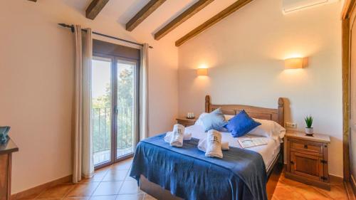 a bedroom with a bed with blue pillows and a window at Casa Rural Noa El Gastor by Ruralidays in El Gastor
