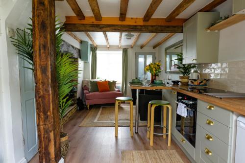 una cocina con armarios verdes y vigas de madera. en Remarkable Cotswolds 1 bedroom cottage in Finstock, 