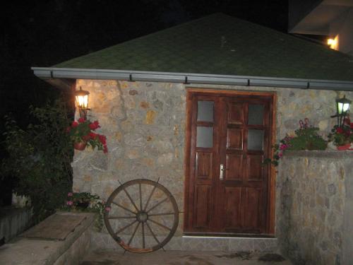 a stone building with a wooden door and a wheel at Apartment Vistanova in Vrdnik