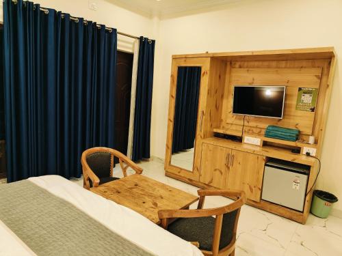 a room with a bed and a table and a television at maharaja resort in Candolim