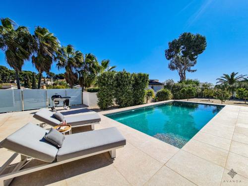 una piscina con due sedie a sdraio accanto a una piscina di Villa moderna de lujo de nueva construcción a 1km de Playa Fustera - Ref A014 AVANOA PREMIUM RENTALS a Benissa