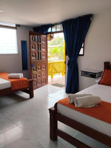 a bedroom with two beds and a door to a balcony at La Rivera Playa Palomino in Palomino