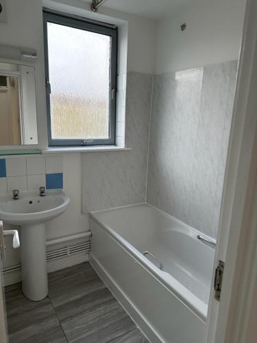 a bathroom with a tub and a sink and a window at Overton in London